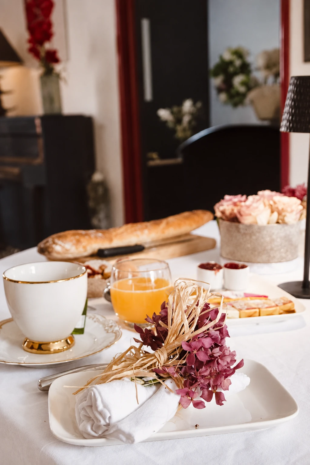Tasse au liseré doré, jus d’orange et linge de table fleuri au petit-déjeuner